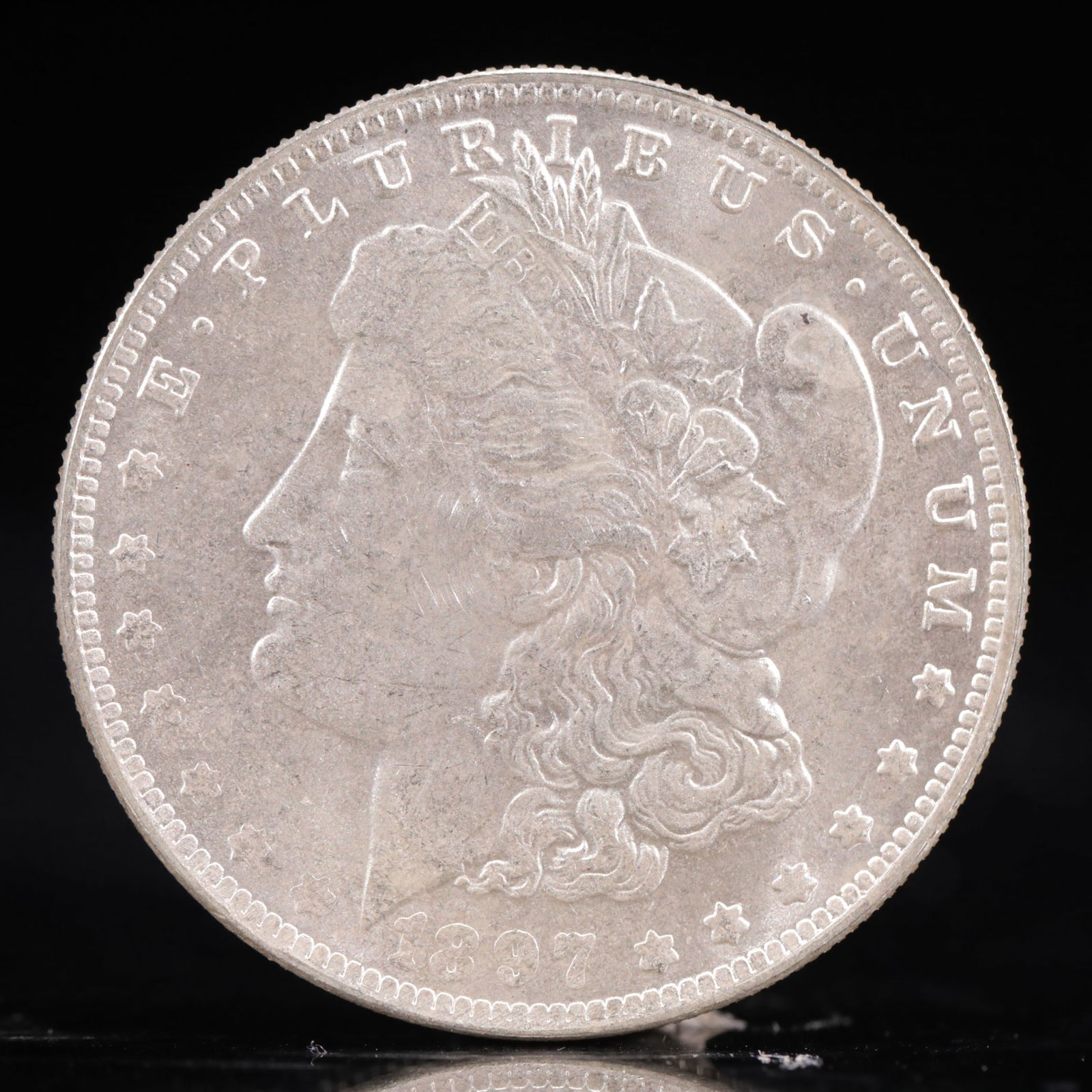 USA Morgan Dollar 1897 Coin: Obv: profile bust with date below and E PLURIBUS UNUM legend and stars around. Rev: eagle with In God we trust above within wreath with UNITED STATES OF AMERICA ONE DOLLAR legend. IN GOD WE TRUST / LI