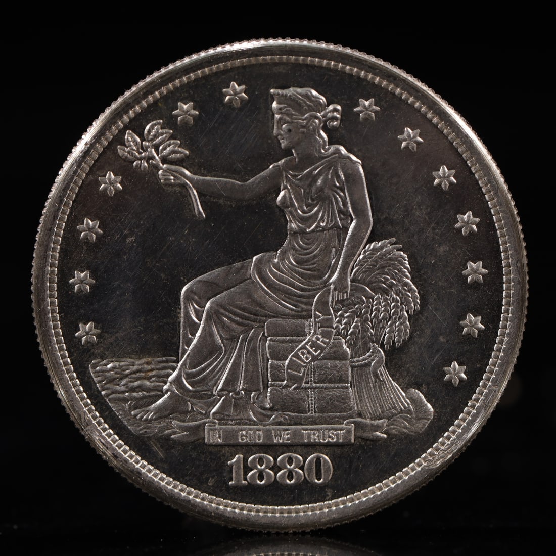 USA Trade Dollar 1880 Coin: American coin. Obverse: Liberty seated on a pedestal facing the sea to the left holding olive branches surrounded by 13 stars. IN GOD WE TRUST / LIBERTY / 1880. Reverse: An eagle holding branches