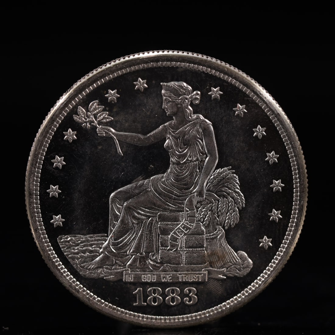 USA Trade Dollar 1883 Coin: American coin. Obverse: Liberty seated on a pedestal facing the sea to the left holding olive branches surrounded by 13 stars. IN GOD WE TRUST / LIBERTY / 1883. Reverse: An eagle holding branches with