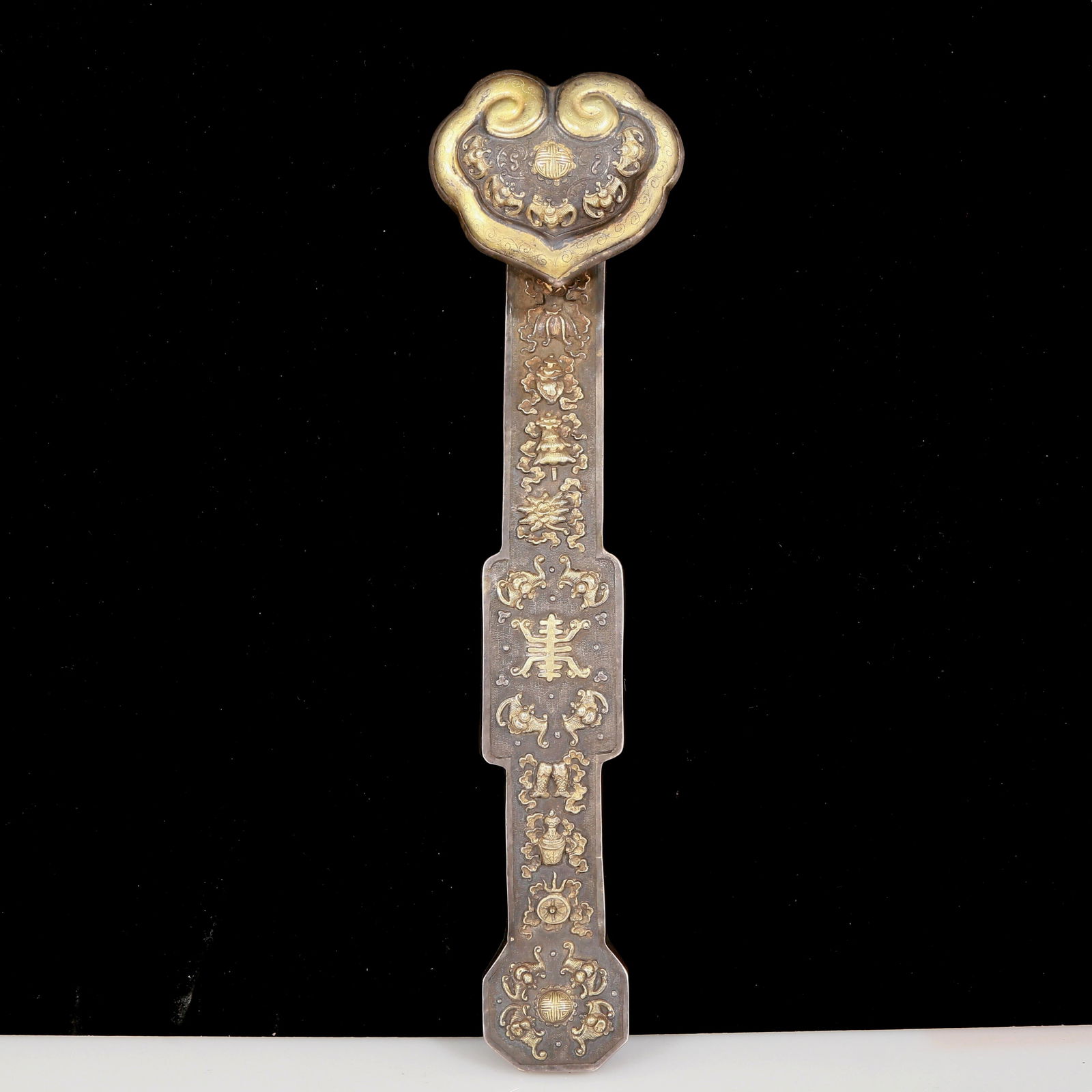 An exquisite gilt bronze and silver eight treasures pattern Ruyi: An exquisite gilt-bronze and silver eight-treasure pattern Ruyi, Qing Dynasty, China. The surface has been carefully carved, vividly demonstrating the superb skills of the craftsmen. It has its own