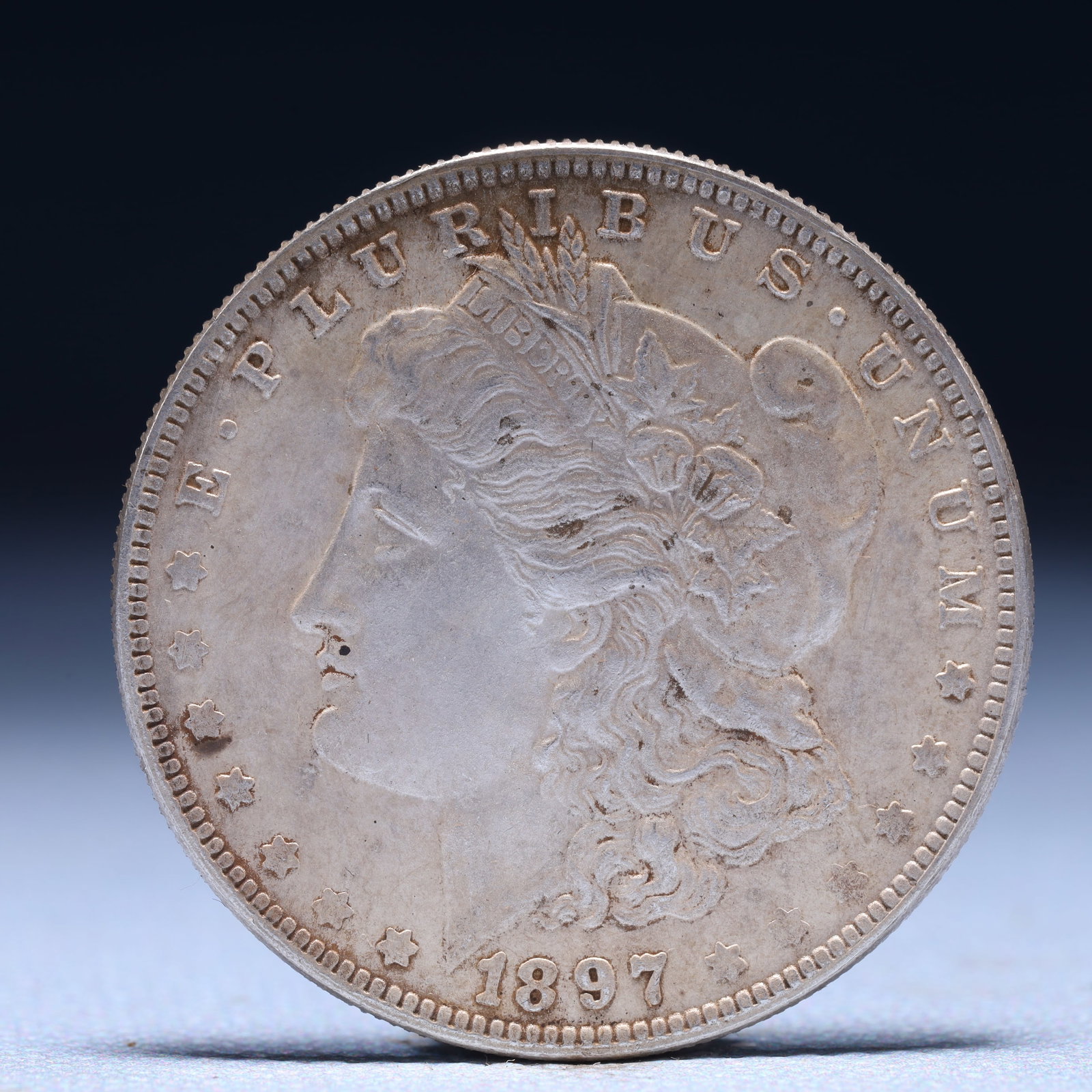 USA Morgan Dollar 1897 Coin: Obv: profile bust with date below and E PLURIBUS UNUM legend and stars around. Rev: eagle with In God we trust above within wreath with UNITED STATES OF AMERICA ONE DOLLAR legend. IN GOD WE TRUST / LI