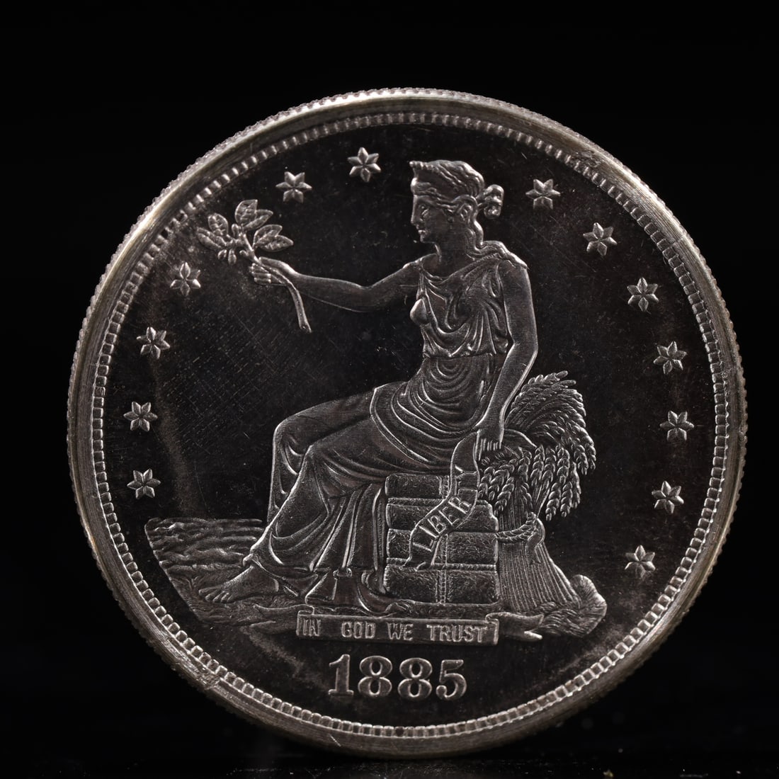 USA Trade Dollar 1885 Coin: American coin. Obverse: Liberty seated on a pedestal facing the sea to the left holding olive branches surrounded by 13 stars. IN GOD WE TRUST / LIBERTY / 1885. Reverse: An eagle holding branches with