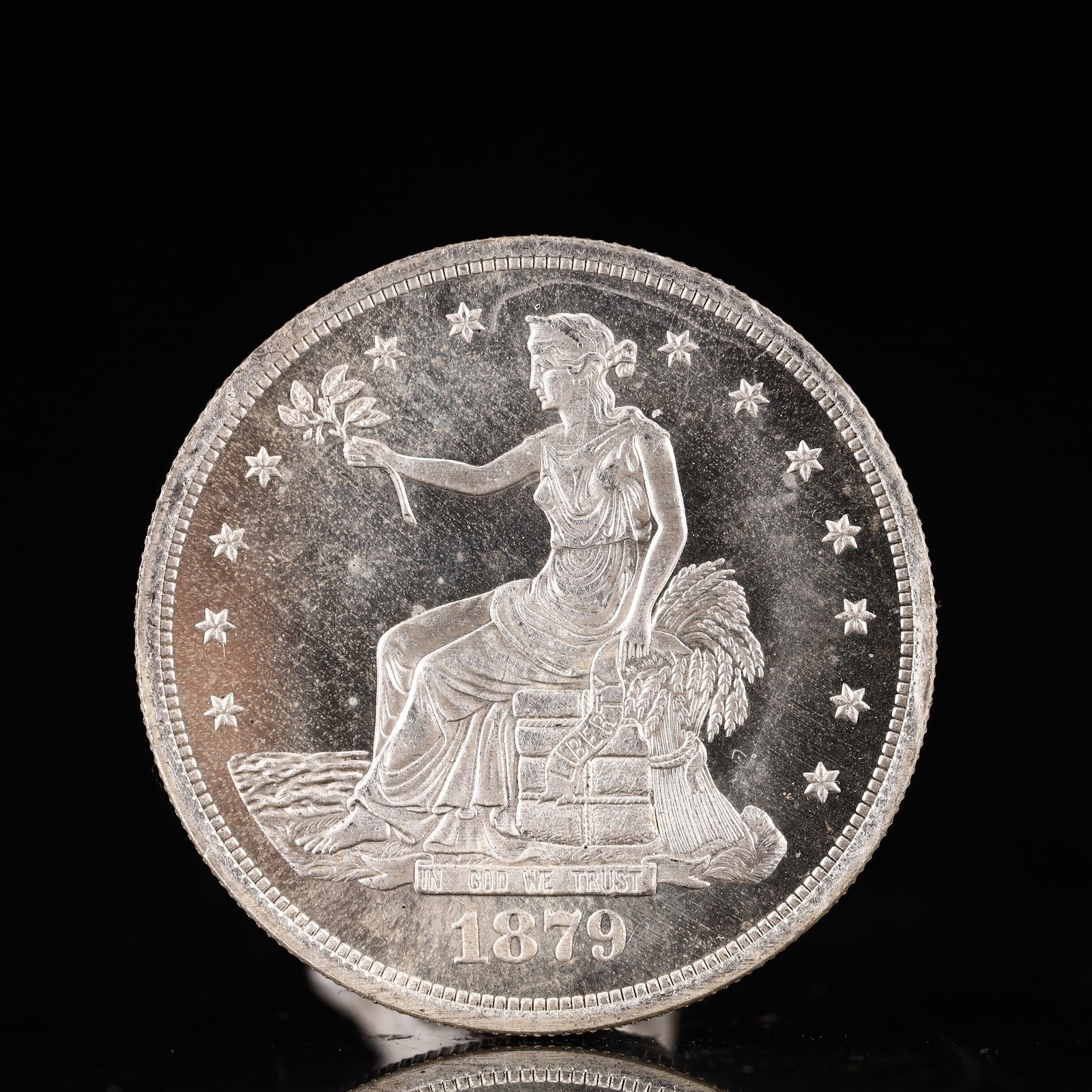 USA Trade Dollar 1879 Coin: American coin. Obverse: Liberty seated on a pedestal facing the sea to the left holding olive branches surrounded by 13 stars. IN GOD WE TRUST / LIBERTY / 1879. Reverse: An eagle holding branches