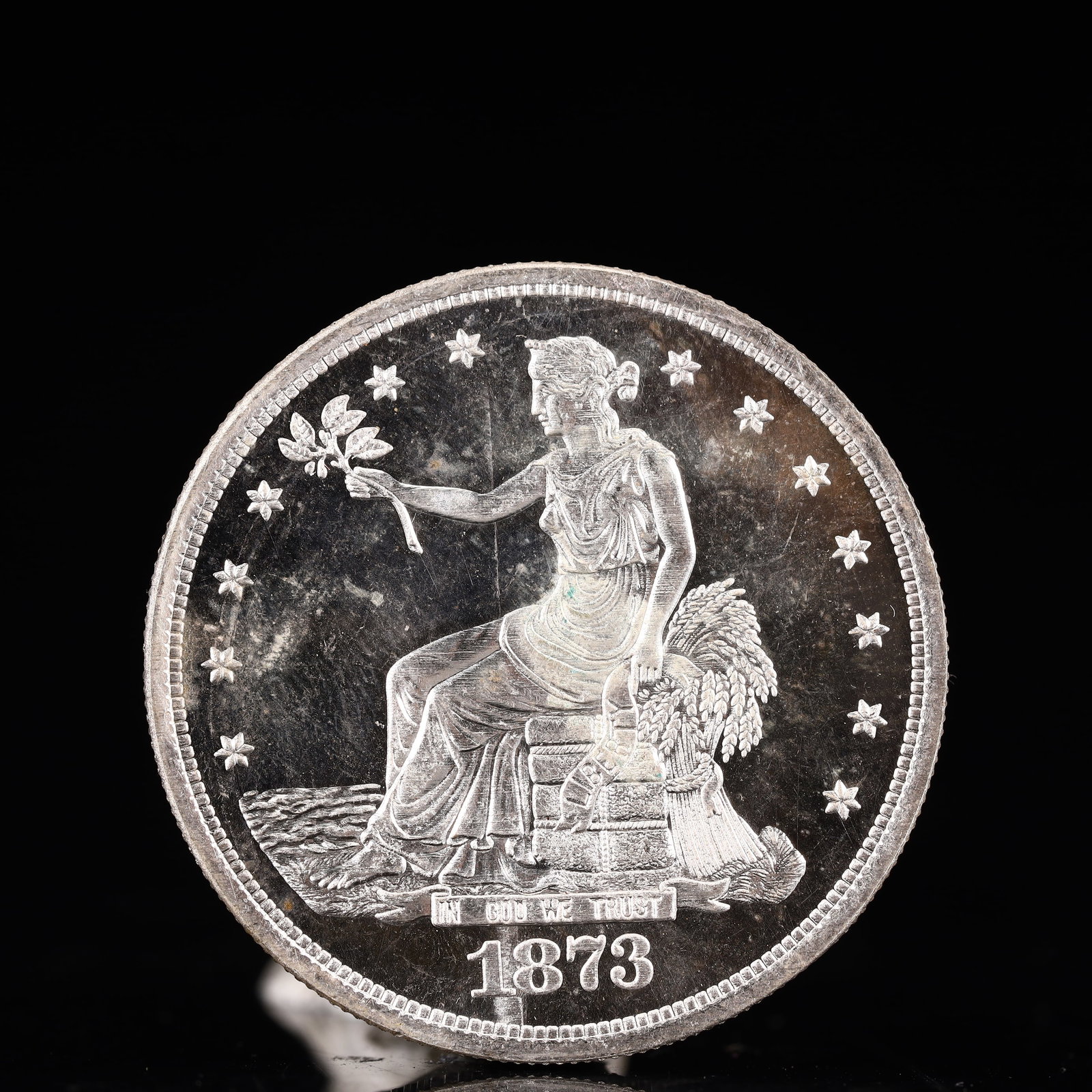 USA Trade Dollar 1873 Coin: American coin. Obverse: Liberty seated on a pedestal facing the sea to the left holding olive branches surrounded by 13 stars. IN GOD WE TRUST / LIBERTY / 1873. Reverse: An eagle holding branches