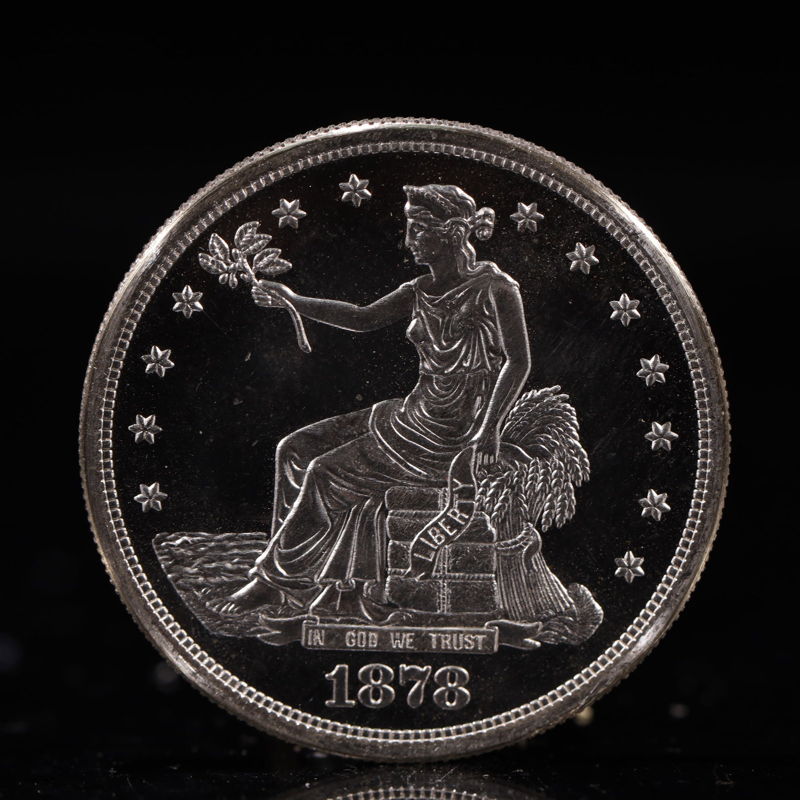 USA Trade Dollar 1878 Coin: American coin. Obverse: Liberty seated on a pedestal facing the sea to the left holding olive branches surrounded by 13 stars. IN GOD WE TRUST / LIBERTY / 1878. Reverse: An eagle holding branches with