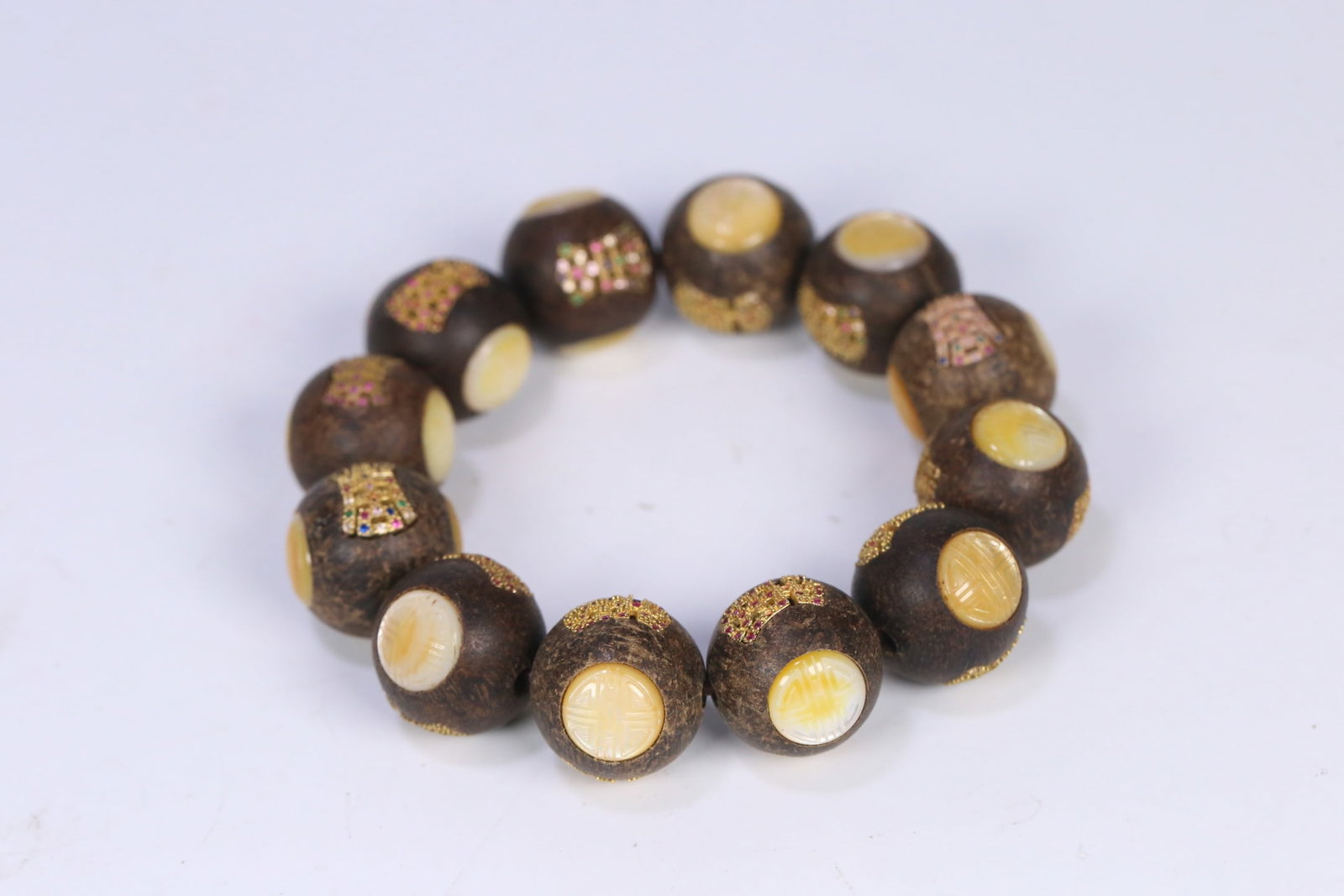 An Exquisite Eaglewood Inlaid Gilt Silver Bracelets: An Exquisite Eaglewood Inlaid Gilt Silver Bracelets Qing Dynasty, China Size:0.8in Weight:65g沉香嵌银鎏金螺钿寿纹手串 中&#