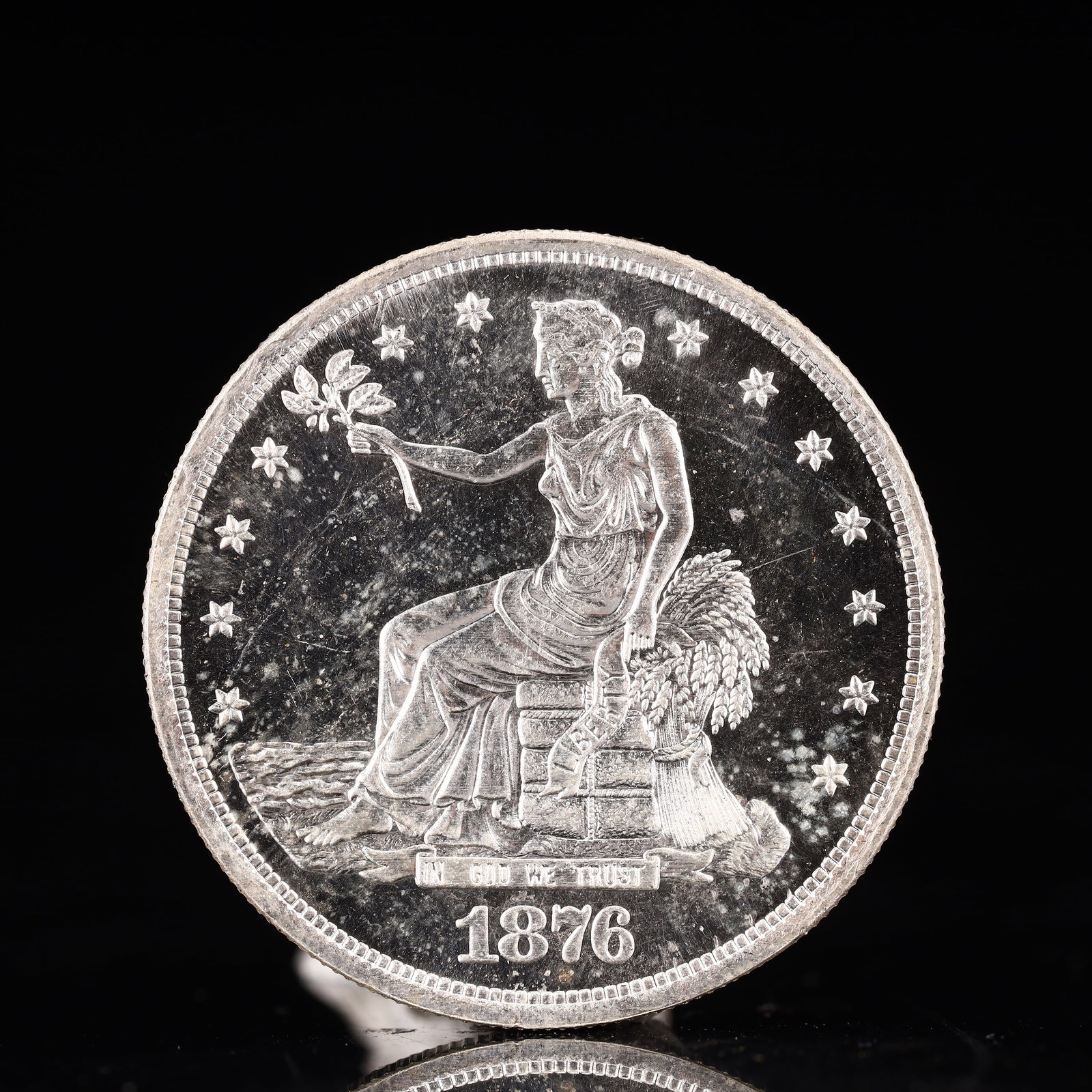 USA Trade Dollar 1876 Coin: American coin. Obverse: Liberty seated on a pedestal facing the sea to the left holding olive branches surrounded by 13 stars. IN GOD WE TRUST / LIBERTY / 1876. Reverse: An eagle holding branches with