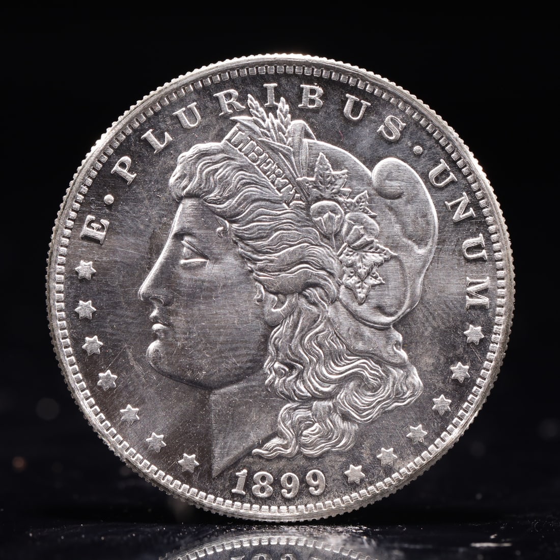 USA Morgan Dollar 1899 Coin: Obv: profile bust with date below and E PLURIBUS UNUM legend and stars around. Rev: eagle with In God we trust above within wreath with UNITED STATES OF AMERICA ONE DOLLAR legend. IN GOD WE TRUST / LI