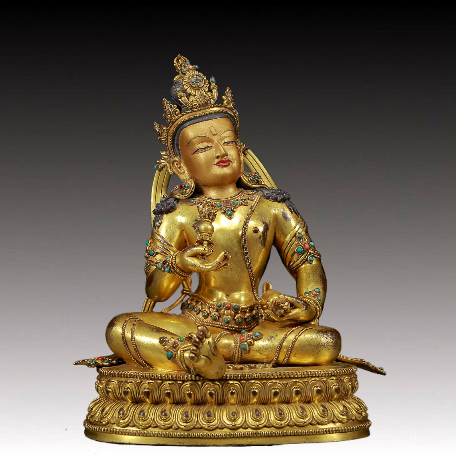 A solemn gilt bronze statue of Vajrasattva inlaid with precious stones: A solemn gilt bronze and gem-inlaid Vajrasattva hammer statue Ming Dynasty, China. The Buddha's face has a solemn expression and his eyes are deep, emitting the mysterious light of compassion and