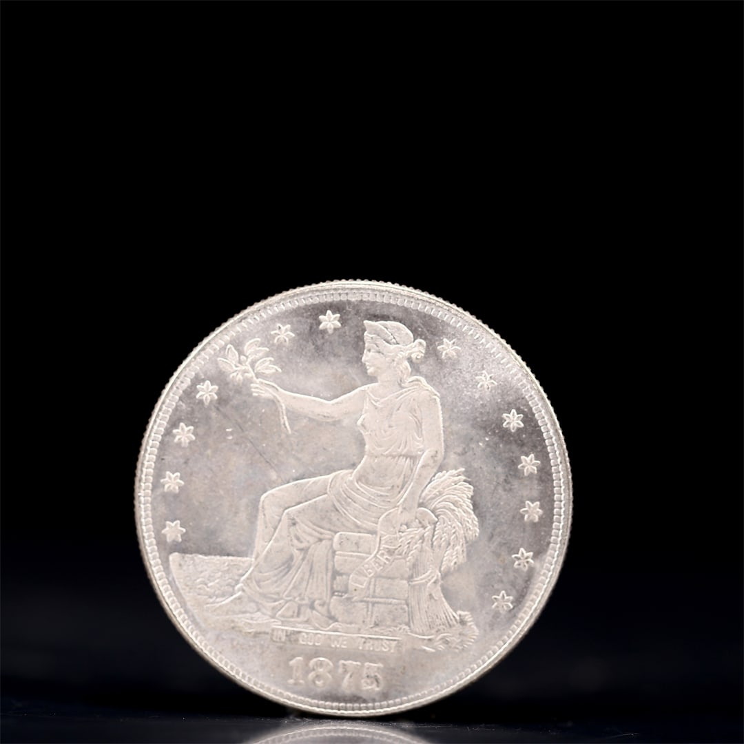 USA Trade Dollar 1875 Coin: American coin. Obverse: Liberty seated on a pedestal facing the sea to the left holding olive branches surrounded by 13 stars. IN GOD WE TRUST / LIBERTY / 1875. Reverse: An eagle holding branches with