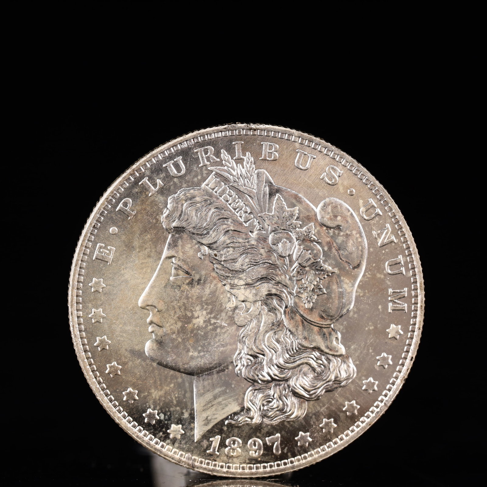 USA Morgan Dollar 1897 Coin: Obv: profile bust with date below and E PLURIBUS UNUM legend and stars around. Rev: eagle with In God we trust above within wreath with UNITED STATES OF AMERICA ONE DOLLAR legend. IN GOD WE TRUST / LI