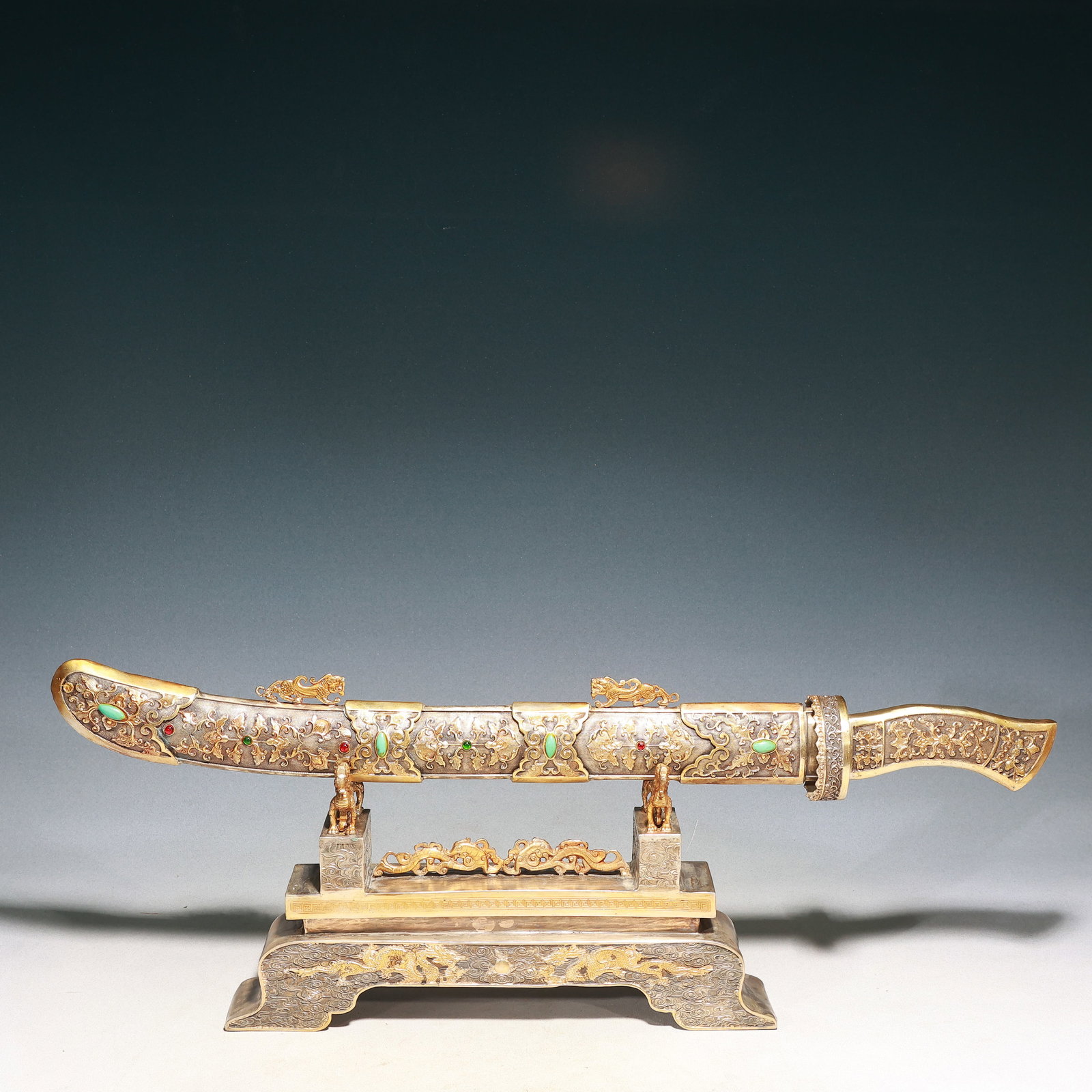 A Huge Silver-Gilt Bronze Lotus and Auspicious Cloud and Dragon Pattern Sword,with Base,Inlaid: A Huge Silver-Gilt Bronze Lotus and Auspicious Cloud and Dragon Pattern Sword,with Base,Inlaid Turquoise and Gems,Qing Dynasty, China,Qianlong Four-character Mark,Size:28.3inx2.8inx10.6in,Weight:5000g