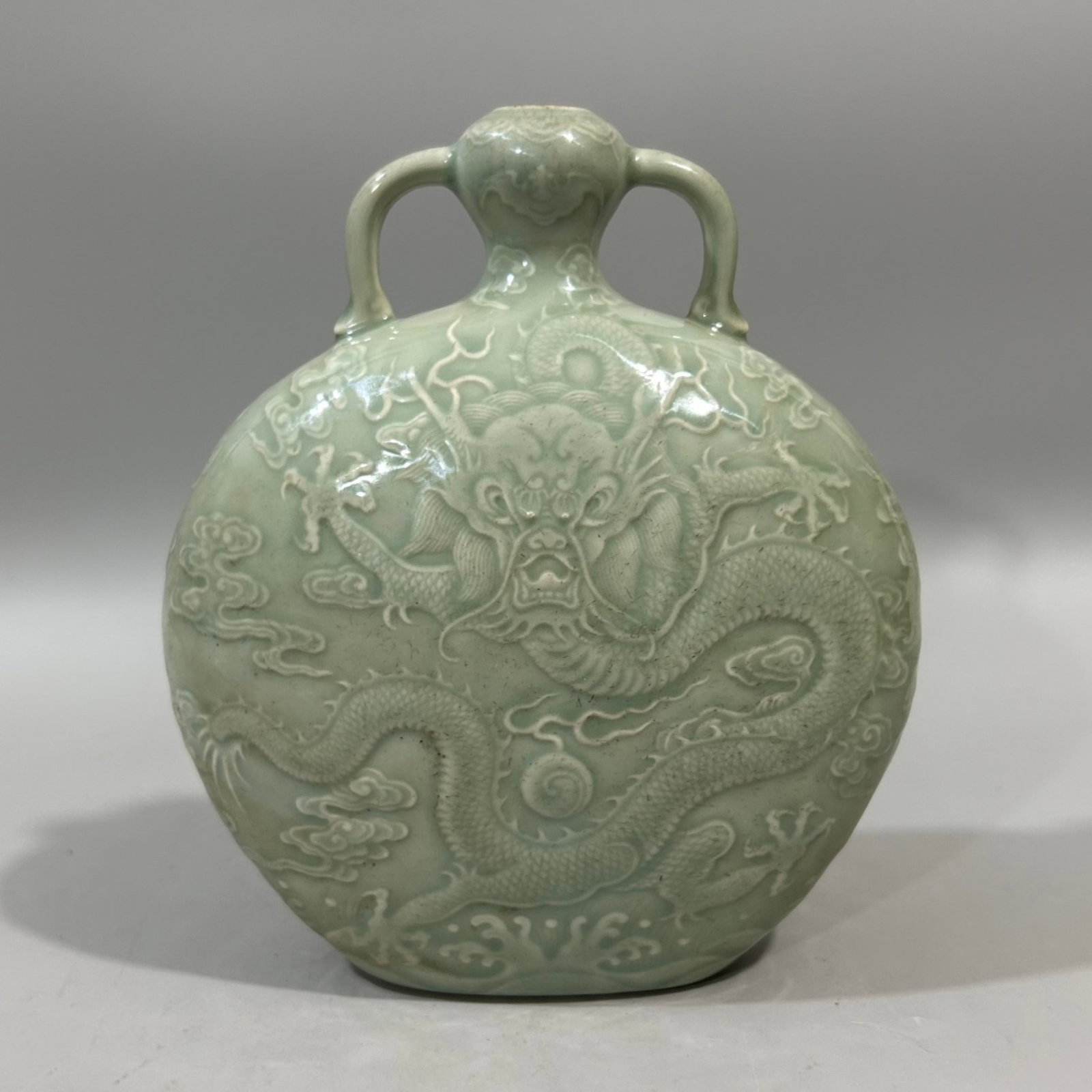An Exquisite Celadon Glazed Auspicious Cloud and Dragon Pattern Double-Ears Vase: An Exquisite Celadon Glazed Auspicious Cloud and Dragon Pattern Double-Ears Vase,Qing Dynasty,China,Qianlong Six-character Mark,Size:6.7inx8.5in 青釉祥云龙纹双