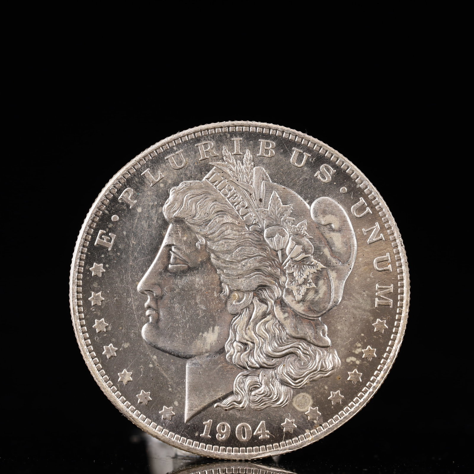 USA Morgan Dollar 1904 Coin: Obv: profile bust with date below and E PLURIBUS UNUM legend and stars around. Rev: eagle with In God we trust above within wreath with UNITED STATES OF AMERICA ONE DOLLAR legend. IN GOD WE TRUST / LI