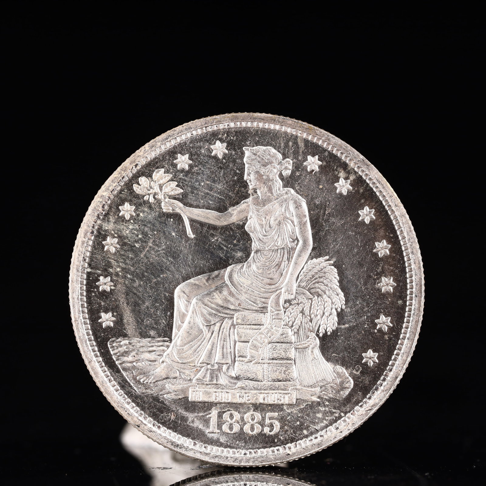 USA Trade Dollar 1885 Coin: American coin. Obverse: Liberty seated on a pedestal facing the sea to the left holding olive branches surrounded by 13 stars. IN GOD WE TRUST / LIBERTY / 1885. Reverse: An eagle holding branches with
