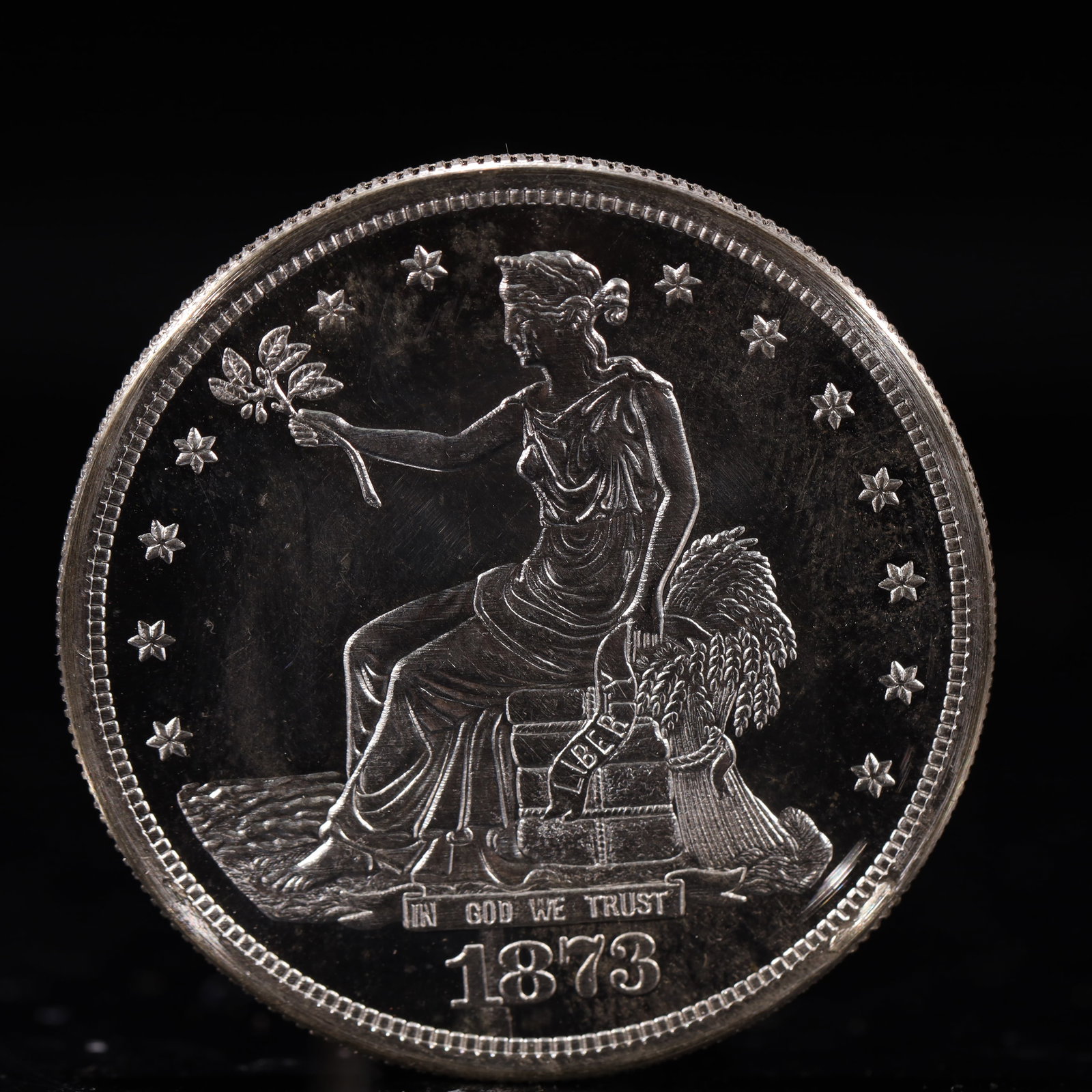 USA Trade Dollar 1873 Coin: American coin. Obverse: Liberty seated on a pedestal facing the sea to the left holding olive branches surrounded by 13 stars. IN GOD WE TRUST / LIBERTY / 1873. Reverse: An eagle holding branches with