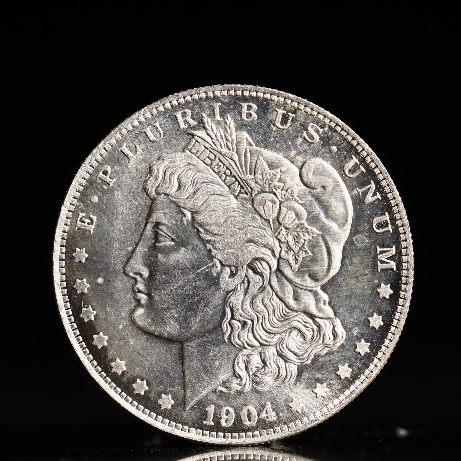 USA Morgan Dollar 1904 Coin: Obv: profile bust with date below and E PLURIBUS UNUM legend and stars around. Rev: eagle with In God we trust above within wreath with UNITED STATES OF AMERICA ONE DOLLAR legend. IN GOD WE TRUST /