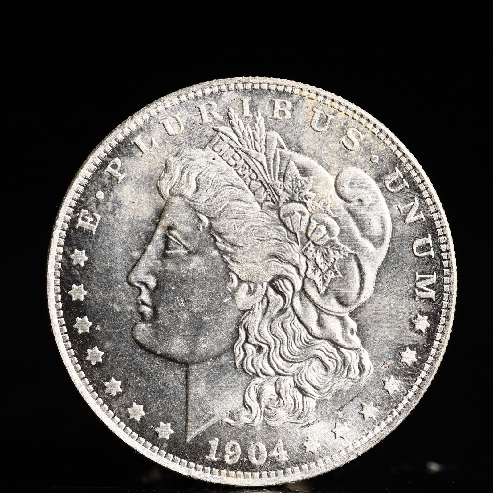 USA Morgan Dollar 1904 Coin: Obv: profile bust with date below and E PLURIBUS UNUM legend and stars around. Rev: eagle with In God we trust above within wreath with UNITED STATES OF AMERICA ONE DOLLAR legend. IN GOD WE TRUST /