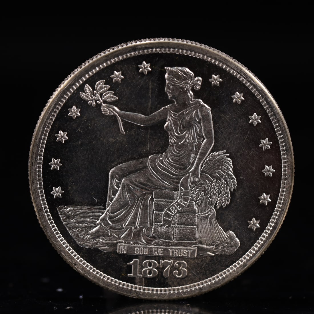 USA Trade Dollar 1873 Coin: American coin. Obverse: Liberty seated on a pedestal facing the sea to the left holding olive branches surrounded by 13 stars. IN GOD WE TRUST / LIBERTY / 1873. Reverse: An eagle holding branches