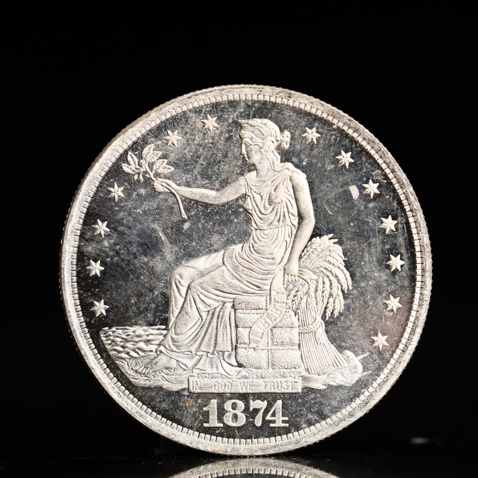 USA Trade Dollar 1874 Coin: American coin. Obverse: Liberty seated on a pedestal facing the sea to the left holding olive branches surrounded by 13 stars. IN GOD WE TRUST / LIBERTY / 1874. Reverse: An eagle holding branches with