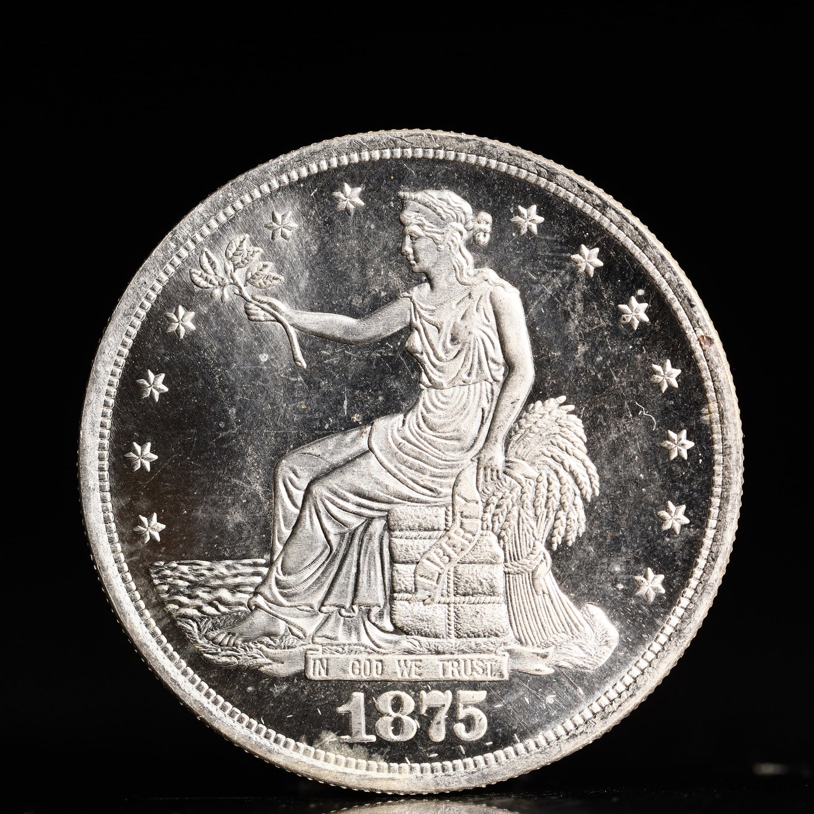 USA Trade Dollar 1875 Coin: American coin. Obverse: Liberty seated on a pedestal facing the sea to the left holding olive branches surrounded by 13 stars. IN GOD WE TRUST / LIBERTY / 1875. Reverse: An eagle holding branches with