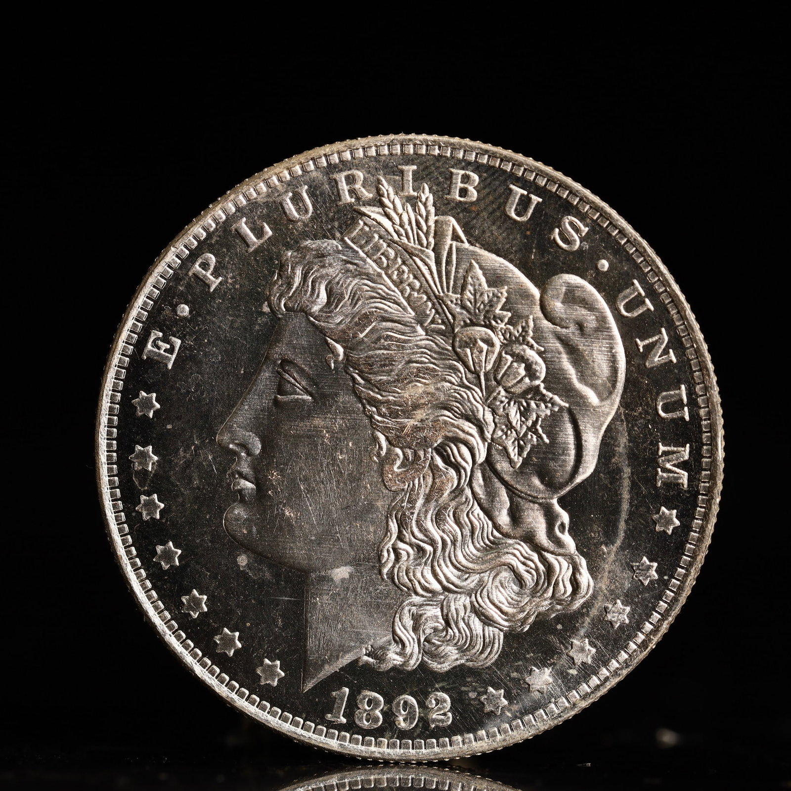 USA Morgan Dollar 1892 Coin: Obv: profile bust with date below and E PLURIBUS UNUM legend and stars around. Rev: eagle with In God we trust above within wreath with UNITED STATES OF AMERICA ONE DOLLAR legend. IN GOD WE TRUST / LI