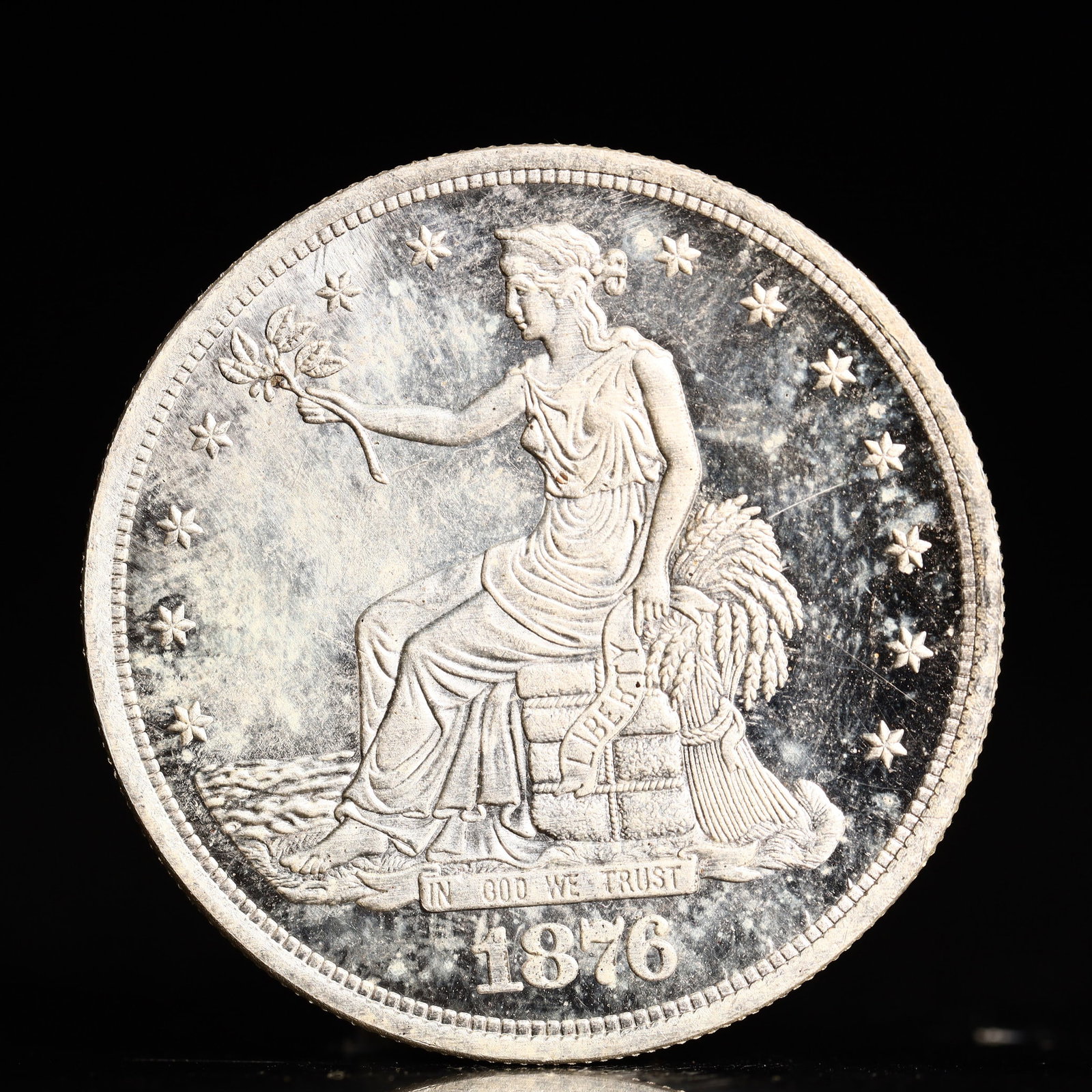 USA Trade Dollar 1876 Coin: American coin. Obverse: Liberty seated on a pedestal facing the sea to the left holding olive branches surrounded by 13 stars. IN GOD WE TRUST / LIBERTY / 1876. Reverse: An eagle holding branches with