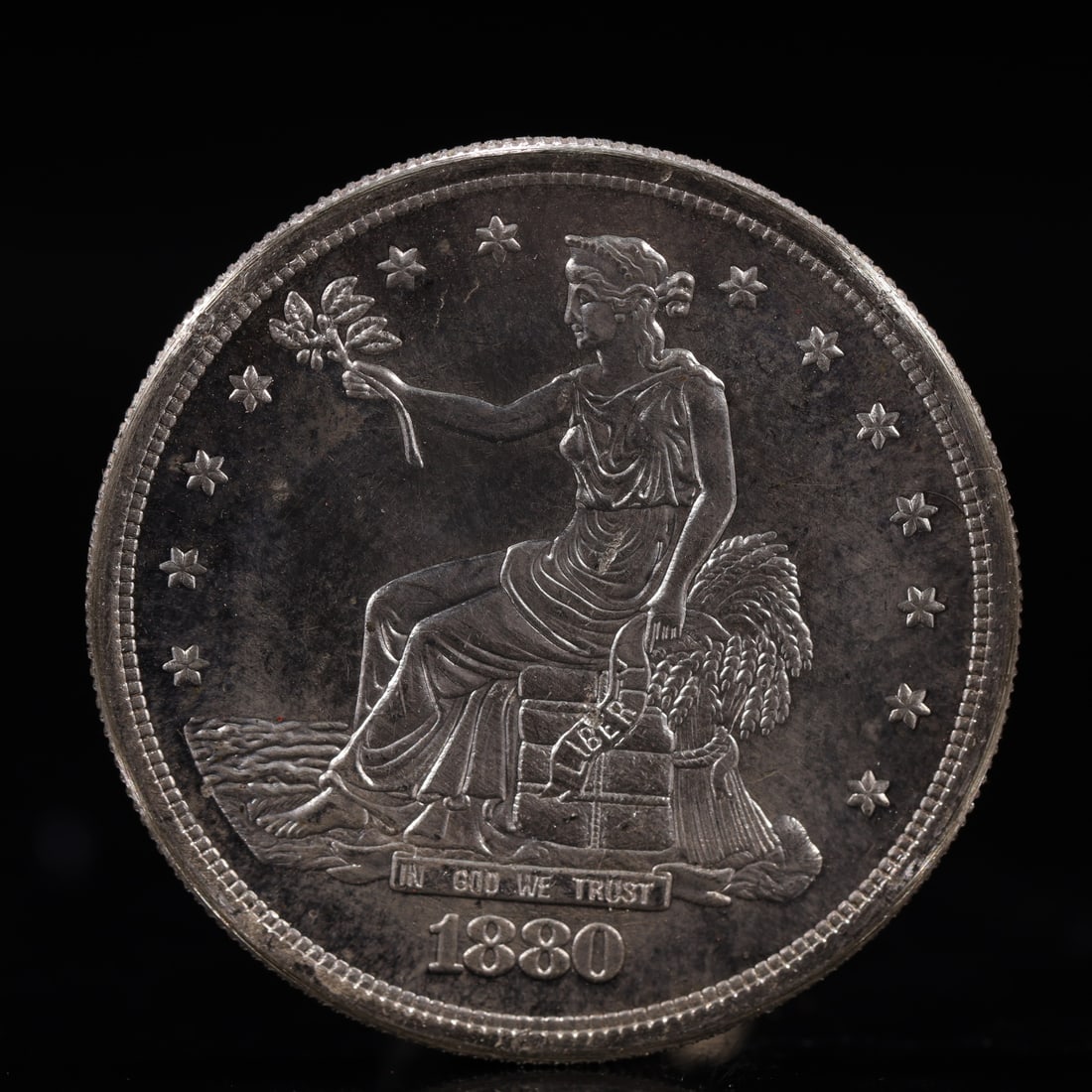 USA Trade Dollar 1880 Coin: American coin. Obverse: Liberty seated on a pedestal facing the sea to the left holding olive branches surrounded by 13 stars. IN GOD WE TRUST / LIBERTY / 1880. Reverse: An eagle holding branches with