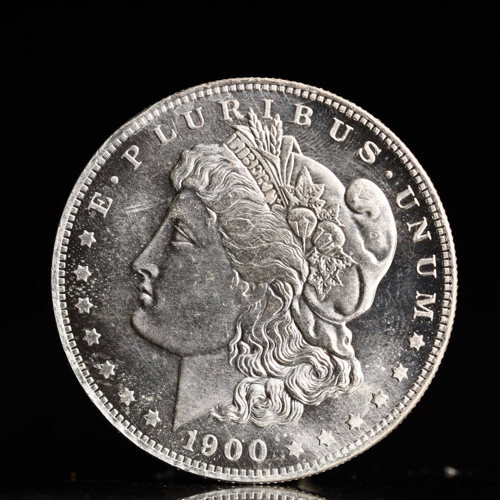 USA Morgan Dollar 1900 Coin: Obv: profile bust with date below and E PLURIBUS UNUM legend and stars around. Rev: eagle with In God we trust above within wreath with UNITED STATES OF AMERICA ONE DOLLAR legend. IN GOD WE TRUST / LI