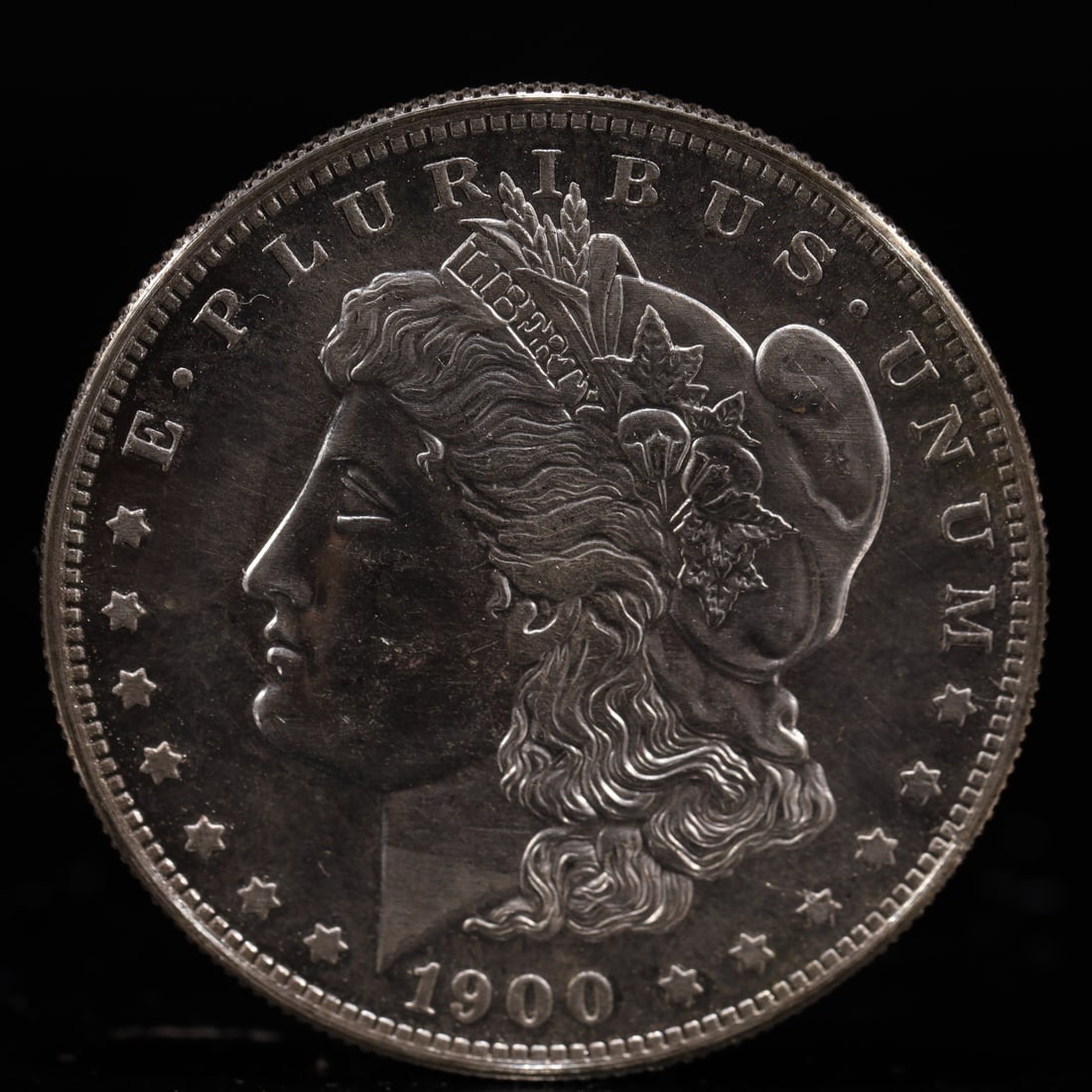 USA Morgan Dollar 1900 Coin: Obv: profile bust with date below and E PLURIBUS UNUM legend and stars around. Rev: eagle with In God we trust above within wreath with UNITED STATES OF AMERICA ONE DOLLAR legend. IN GOD WE TRUST / LI