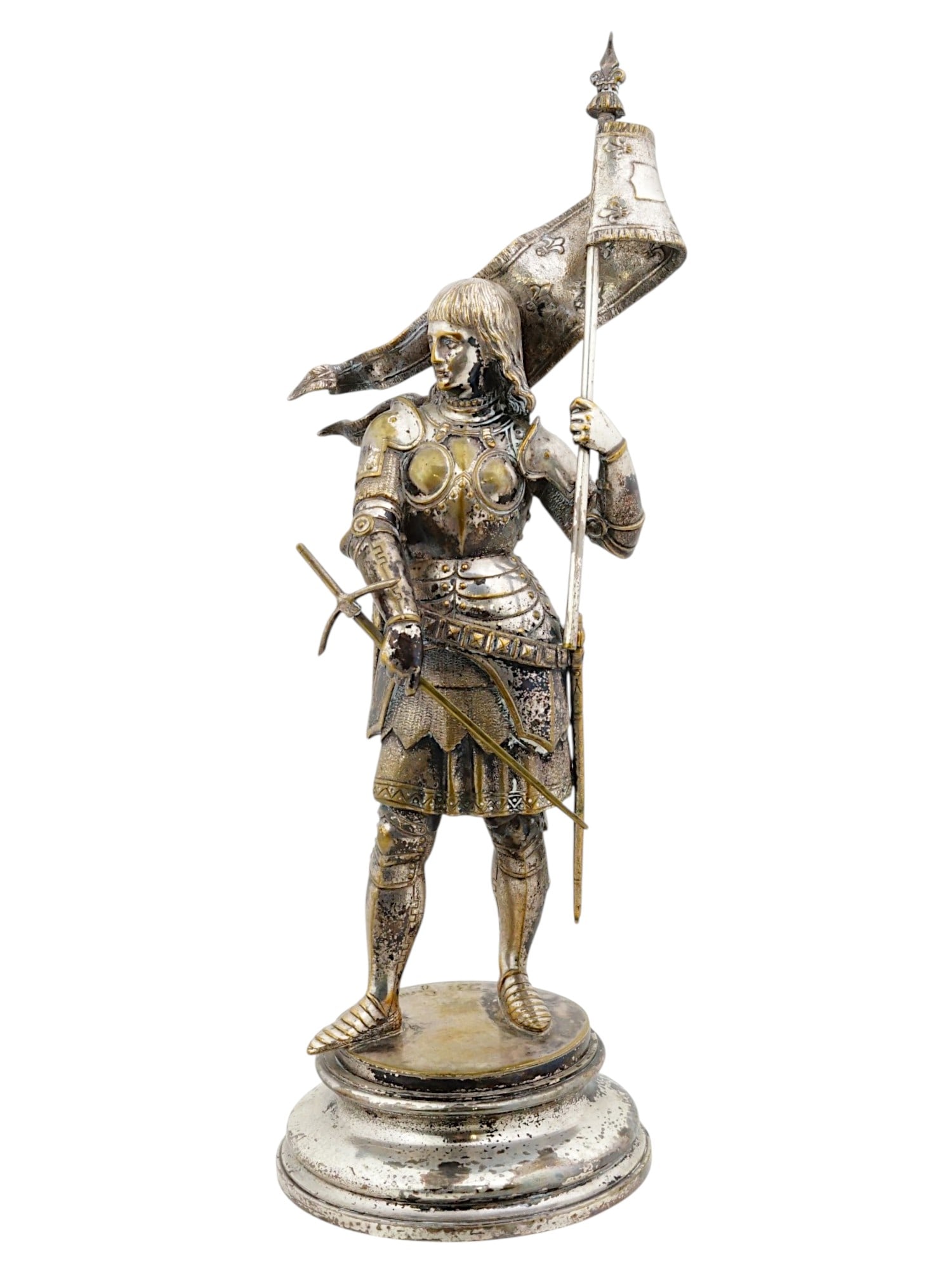 ANTIQUE FRENCH SILVER PLATED JOAN OF ARC STATUE: This antique 19th-century French silver-plated figure depicts Joan of Arc clad in detailed plate armor, standing resolutely while holding a flowing banner adorned with fleur-de-lis motifs in her left 