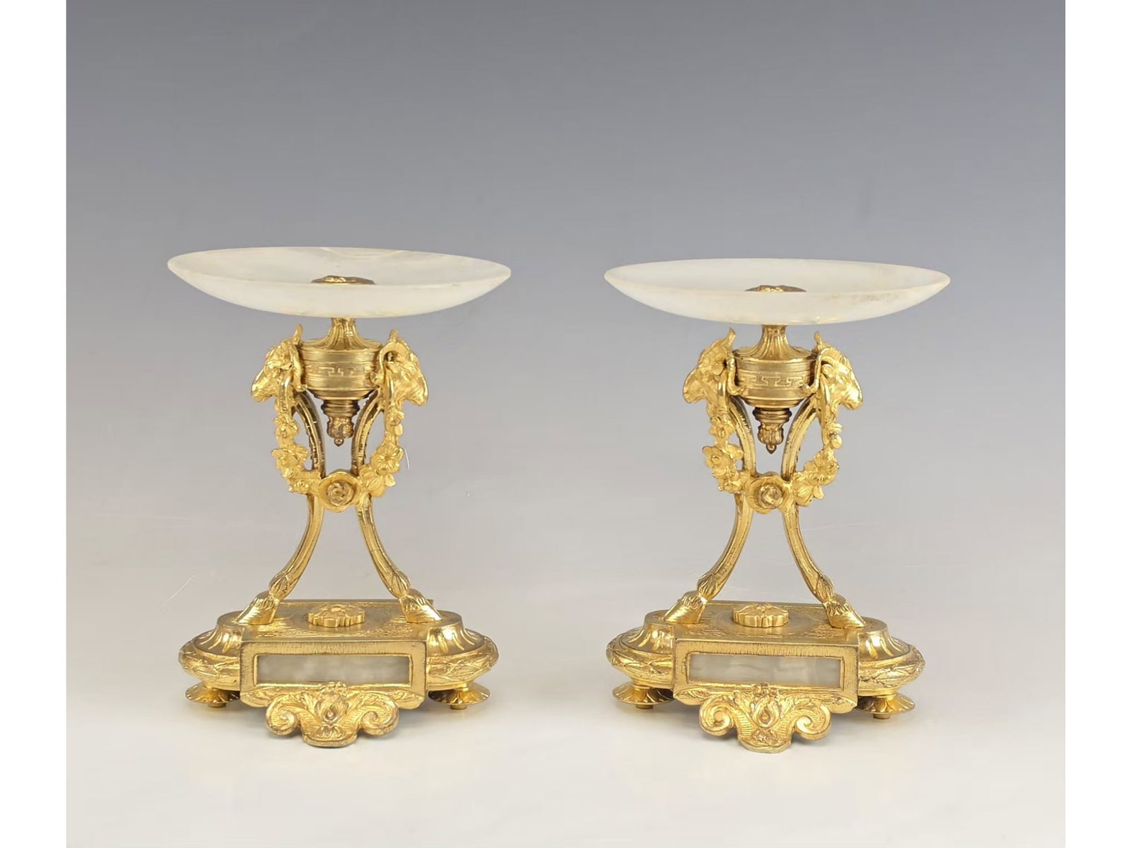 FRENCH 19TH CENTURY GILT BRONZE AND ONYX TAZZAS PAIR: Crafted in 19th-century France, this fine pair of decorative table compotes showcases the neoclassical style. The cast alloy supports are designed as classical animalistic tripod legs ending in hooves
