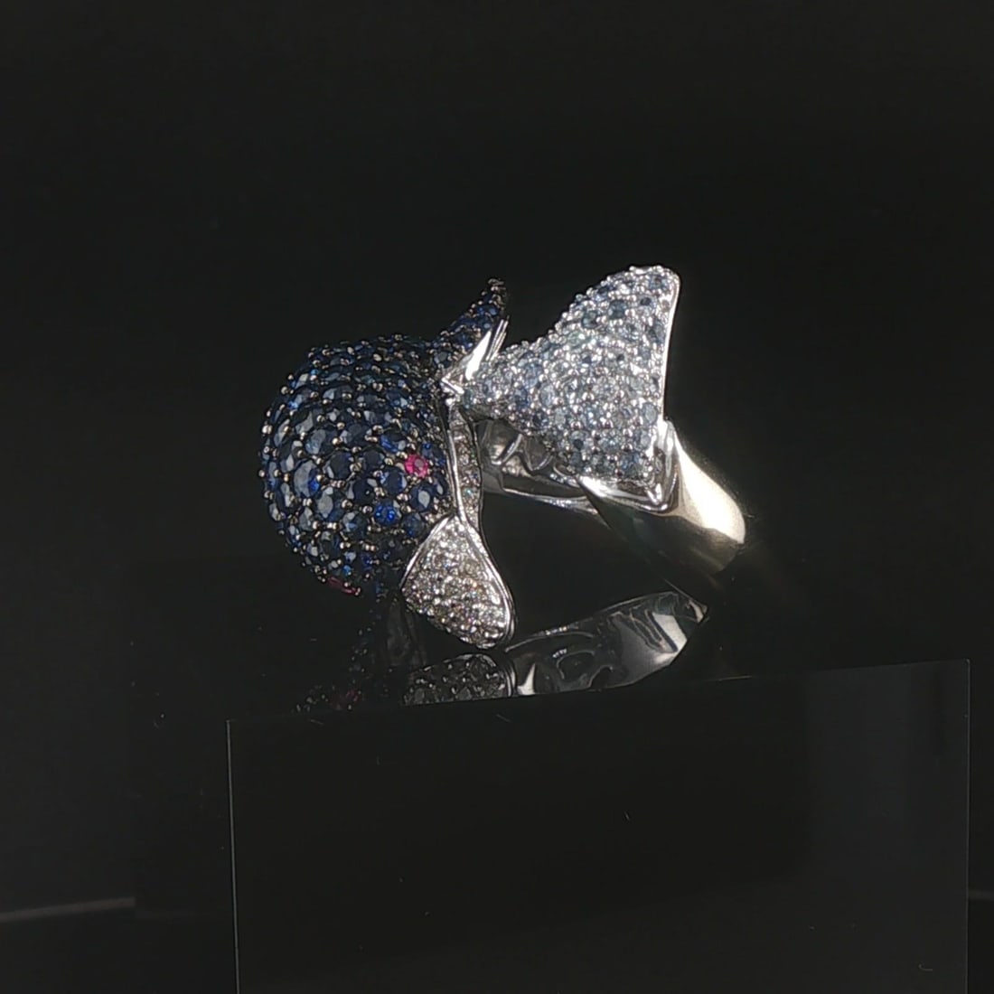 18k White Gold Blue Sapphire Ruby and Diamond Bypass Dolphin Ring Size 7: Condition: Excellent Condition, Professionally Cleaned Metal: 18k Gold (Marked, and Professionally Tested) Weight: 13.5g Gemstones: Round Cut Blue Sapphires Gemstones: Two Round Cut Rubies (Eyes) Diam