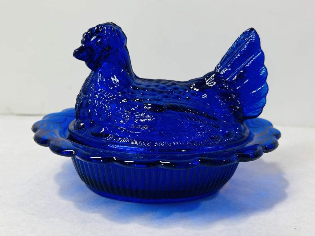 Mosser Cobalt Blue Glass Hen on Nest Covered Dish: This two-piece pressed glass covered dish is fashioned in the classic form of a hen on a nest, rendered in a deep cobalt blue color. The lid is molded into the shape of a hen with detailed feathering 