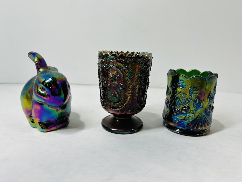 A Trio of Iridescent Carnival Glass Decorative Items: A collection of three iridescent carnival glass objects comprising a seated rabbit figurine and two small vessels. The rabbit figurine exhibits a strong multi-colored iridescent finish over a dark gla