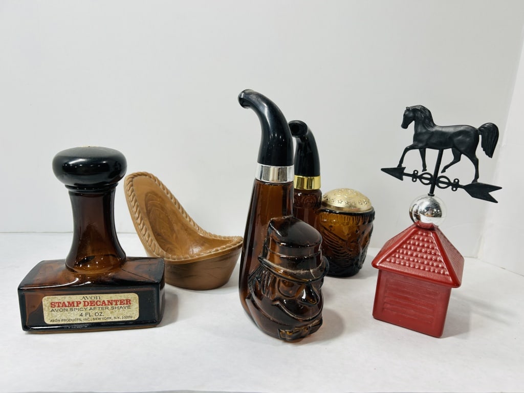 Vintage Avon Novelty Glass and Plastic Aftershave Decanters: This group consists of various novelty fragrance decanters produced by Avon Products, Inc. The collection includes a stamp-shaped decanter made of amber glass with a black plastic cap, featuring a pap