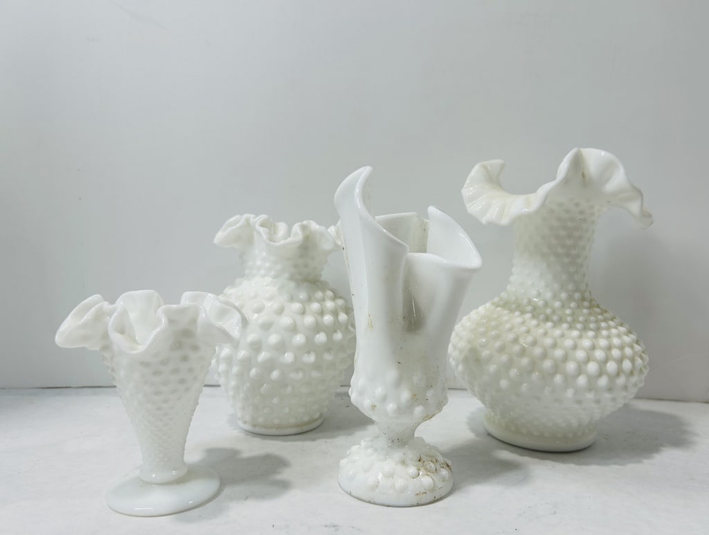 White Hobnail Milk Glass Vases, Attributed to Fenton: A collection of white milk glass vases featuring an all-over hobnail pattern, attributed to Fenton. The group includes various forms, such as a footed trumpet-shaped vase with a ruffled rim, a bulbous