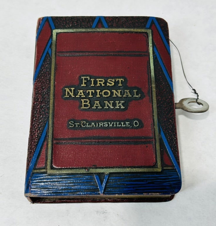 Bankers Utilities Co. First National Bank of St. Clairsville Ohio Book Form Pocket Savings Bank: This vintage book-form pocket savings bank was manufactured by the Bankers Utilities Co. of San Francisco, California. The item is constructed with a metal body featuring a polychrome, embossed textur