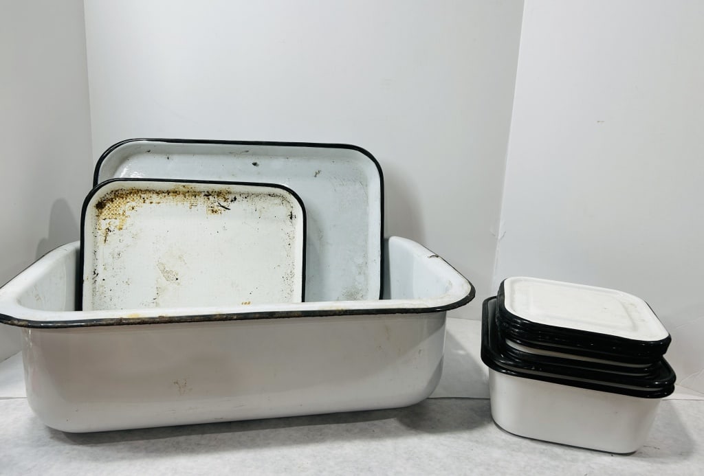 Vintage White Enamelware Utility Pieces with Black Rims: This collection consists of several white enamelware items featuring a characteristic black-trimmed rim. The assortment includes a large rectangular basin, multiple flat trays of varying dimensions, a