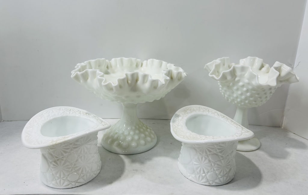Fenton White Milk Glass Pedestal Bowls and Top Hat Vases: Attributed to Fenton, this collection of opaque white milk glass decorative items includes pedestal bowls and vessels formed in the shape of top hats. The bowls feature ruffled, crimped rims and hobna