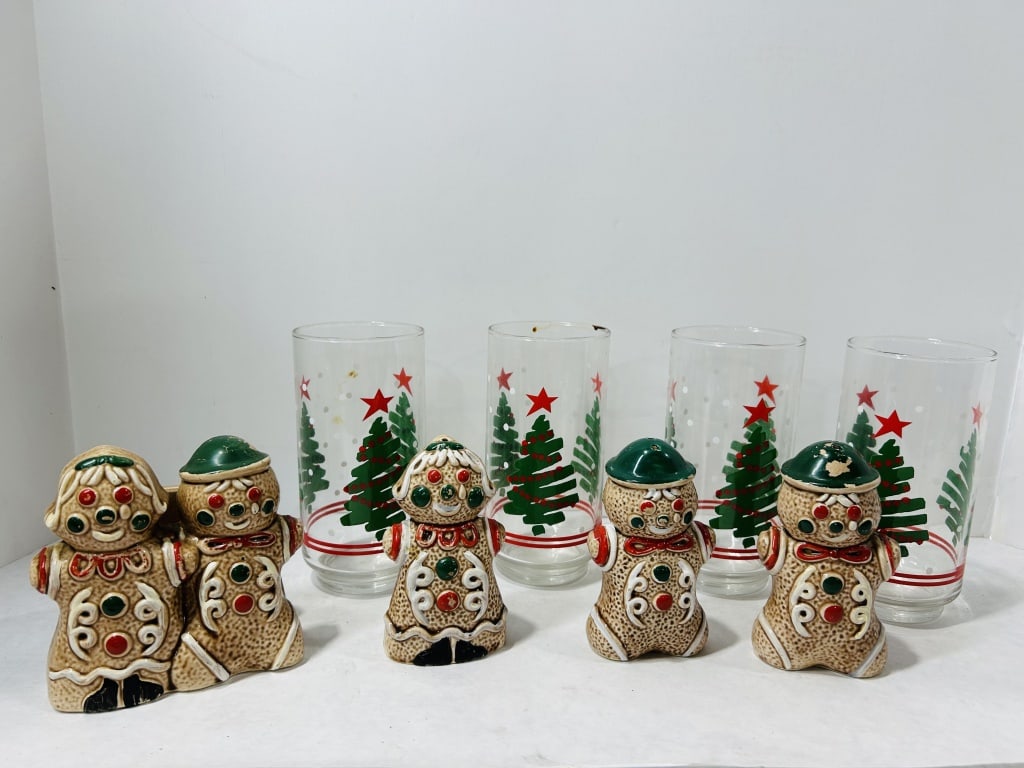 Vintage Holiday Tableware Including Glass Tumblers and Ceramic Gingerbread Figures: A collection of vintage Christmas-themed tableware items. The group includes several clear glass tumblers featuring a screen-printed holiday motif. The decoration consists of stylized green Christmas 