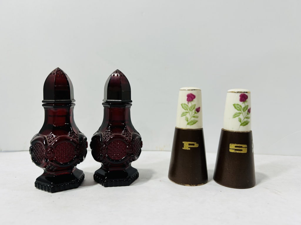 Vintage Salt and Pepper Shakers: This collection consists of two pairs of vintage salt and pepper shakers. One pair is crafted from deep ruby red pressed glass, featuring bulbous bodies with molded geometric and textured designs. The