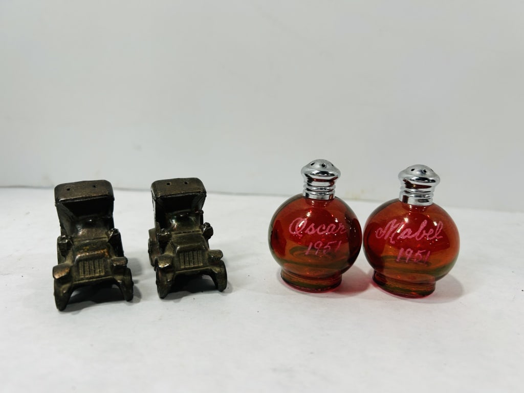 Vintage Metal and Ruby Glass Salt and Pepper Shakers: An assortment of vintage salt and pepper shakers, including examples resembling mid-century miniature bottles produced by Avon. This collection features a pair of globular ruby red glass shakers fitte