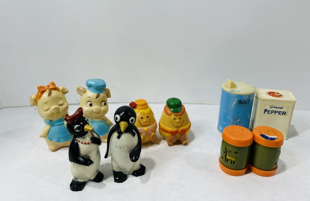 Mid-Century Novelty Plastic and Ceramic Salt and Pepper Shakers: An assortment of various vintage novelty salt and pepper shakers and dispensers, primarily made of molded plastic and ceramic. The group features two anthropomorphic pig shakers in blue and yellow att