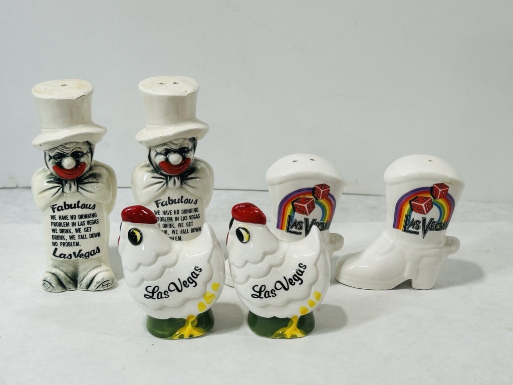Vintage Las Vegas Novelty Salt and Pepper Shakers: A collection of vintage glazed ceramic novelty salt and pepper shakers featuring various Las Vegas souvenir designs. The group includes several sets of shakers. One pair is modeled as whimsical figure