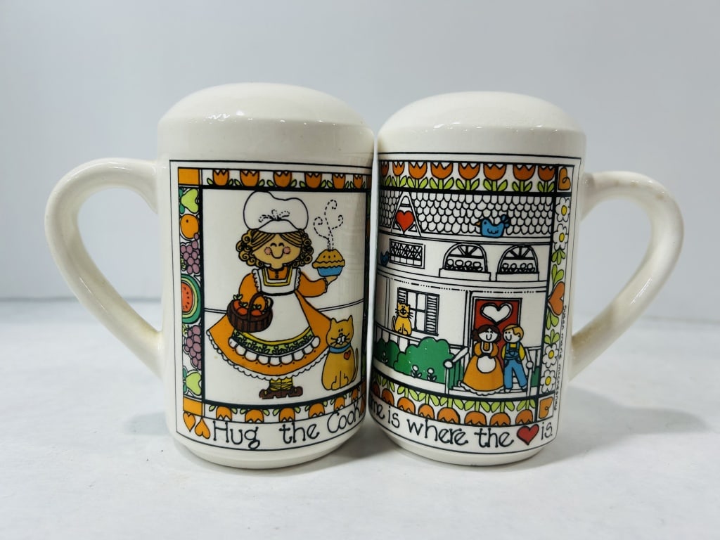 A Pair of Susan Marie McChesney Ceramic Mug-Form Salt and Pepper Shakers: A pair of glazed ceramic salt and pepper shakers designed in the form of miniature mugs with integral handles. Each shaker features colorful folk-art illustrations. One shaker depicts a figure in a ch