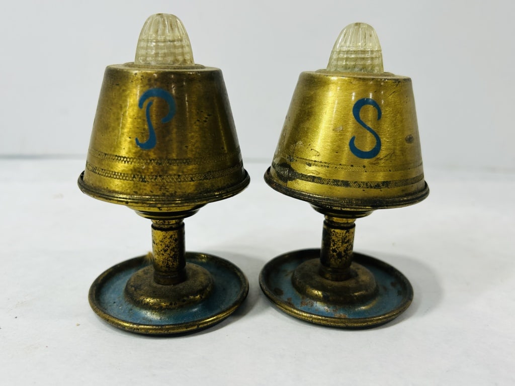 A Pair of Mid-Century Modern Novelty Lamp-Form Salt and Pepper Shakers: This lot comprises a pair of vintage novelty salt and pepper shakers designed in the form of miniature table lamps. The shakers are constructed from a gold-toned metal with conical bodies featuring te