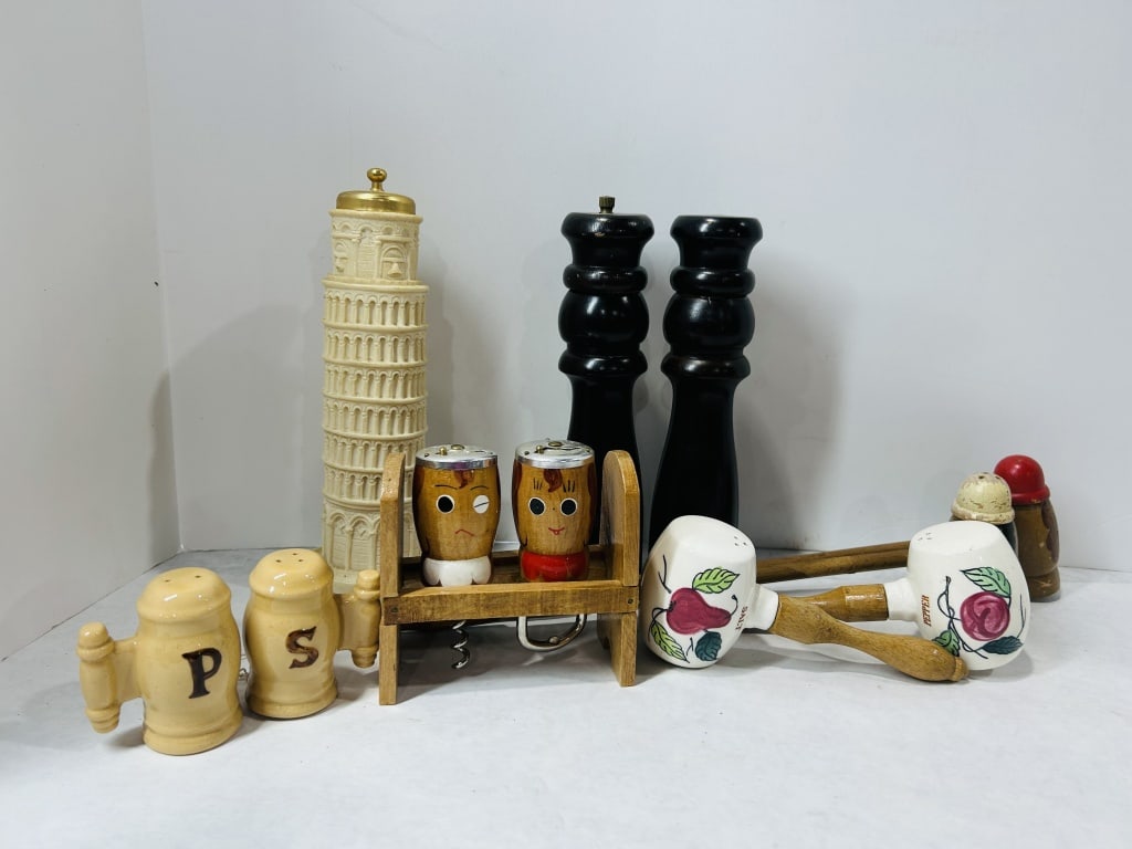 Vintage Novelty Salt and Pepper Shakers and Kitchen Accessories: A collection of various vintage and novelty salt and pepper shakers and related kitchenware. The assortment includes a resin souvenir shaker modeled as the Leaning Tower of Pisa featuring a gold-toned