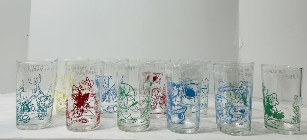 A Collection of Flintstones Hanna-Barbera Character Glass Tumblers, 1964: A collection of clear glass drinking tumblers featuring printed character illustrations from the Hanna-Barbera animated series The Flintstones. These items are widely attributed to Welch's jelly as pr