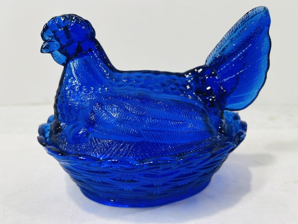 Cobalt Blue Pressed Glass Hen on Nest Covered Dish: A two-piece figural covered dish rendered in cobalt blue pressed glass. The lid is molded in the form of a nesting hen, featuring textured feathering across the wings and breast and an upright, ribbed